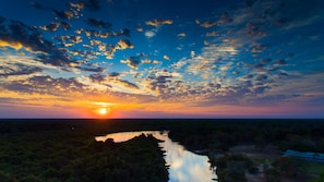 A sunset over a river with a bridge in the distance.