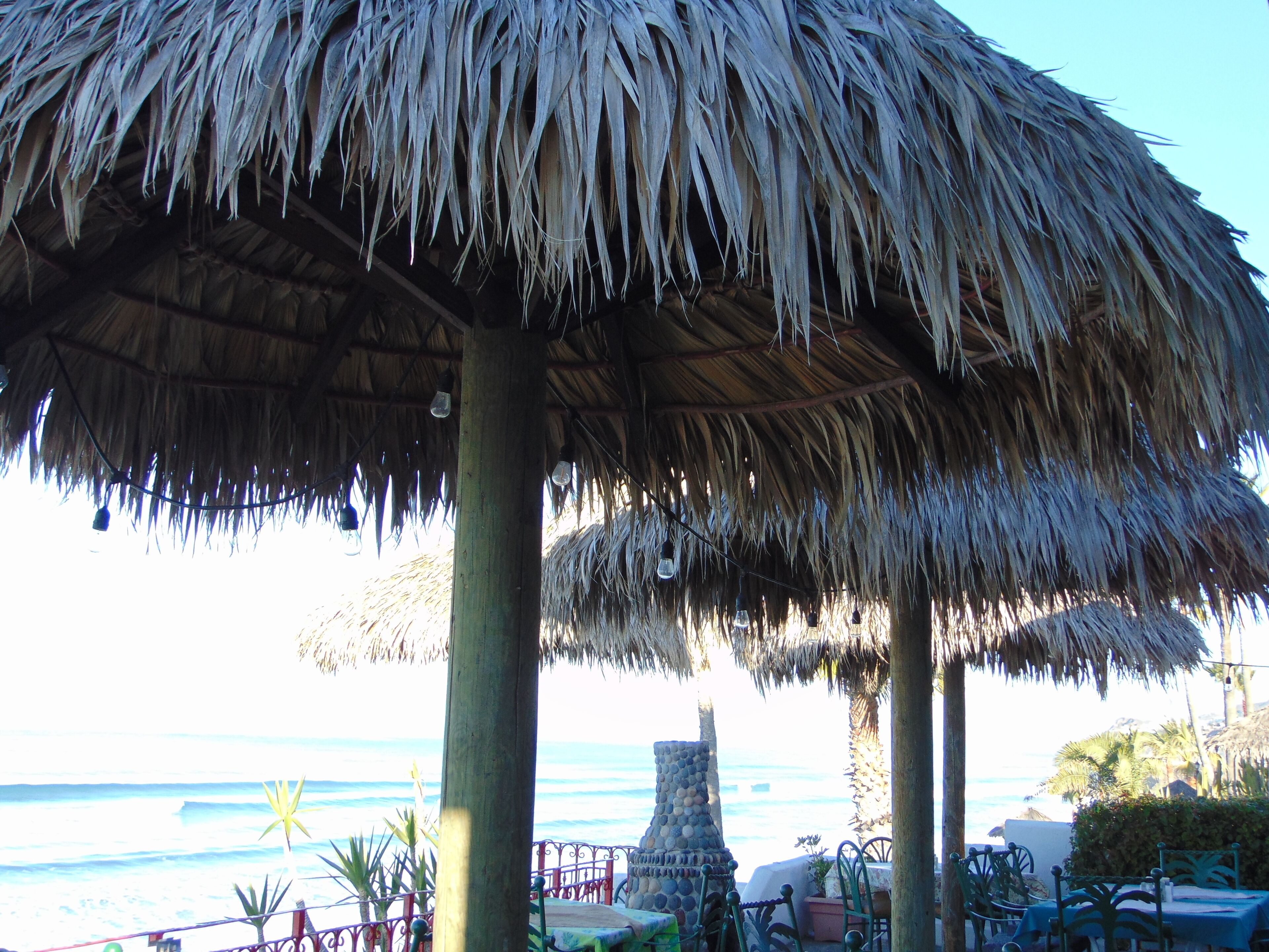 A beachside thatched umbrella structure with a view of the ocean.