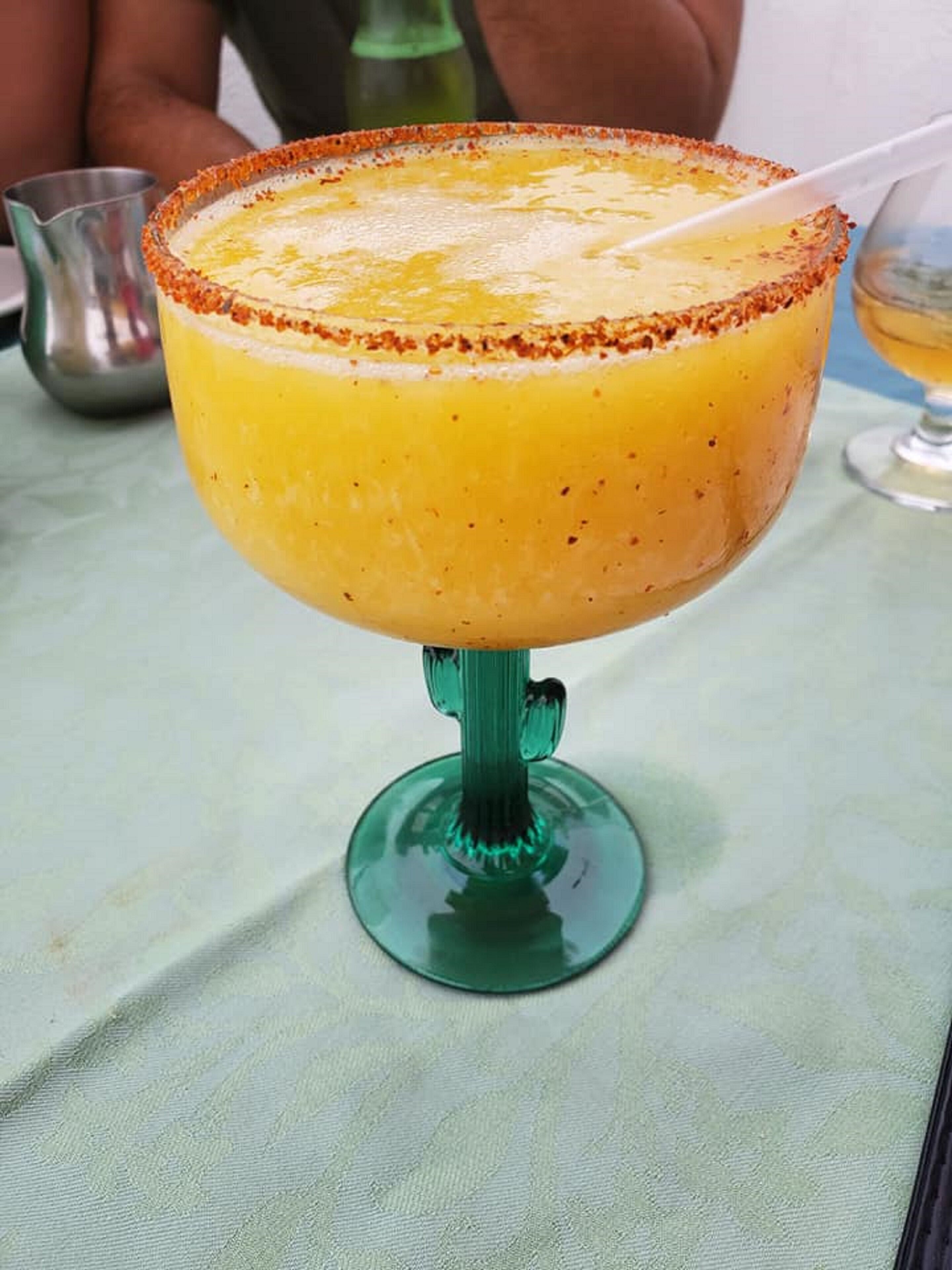 Un margarita in un bicchiere verde con bordo salato.