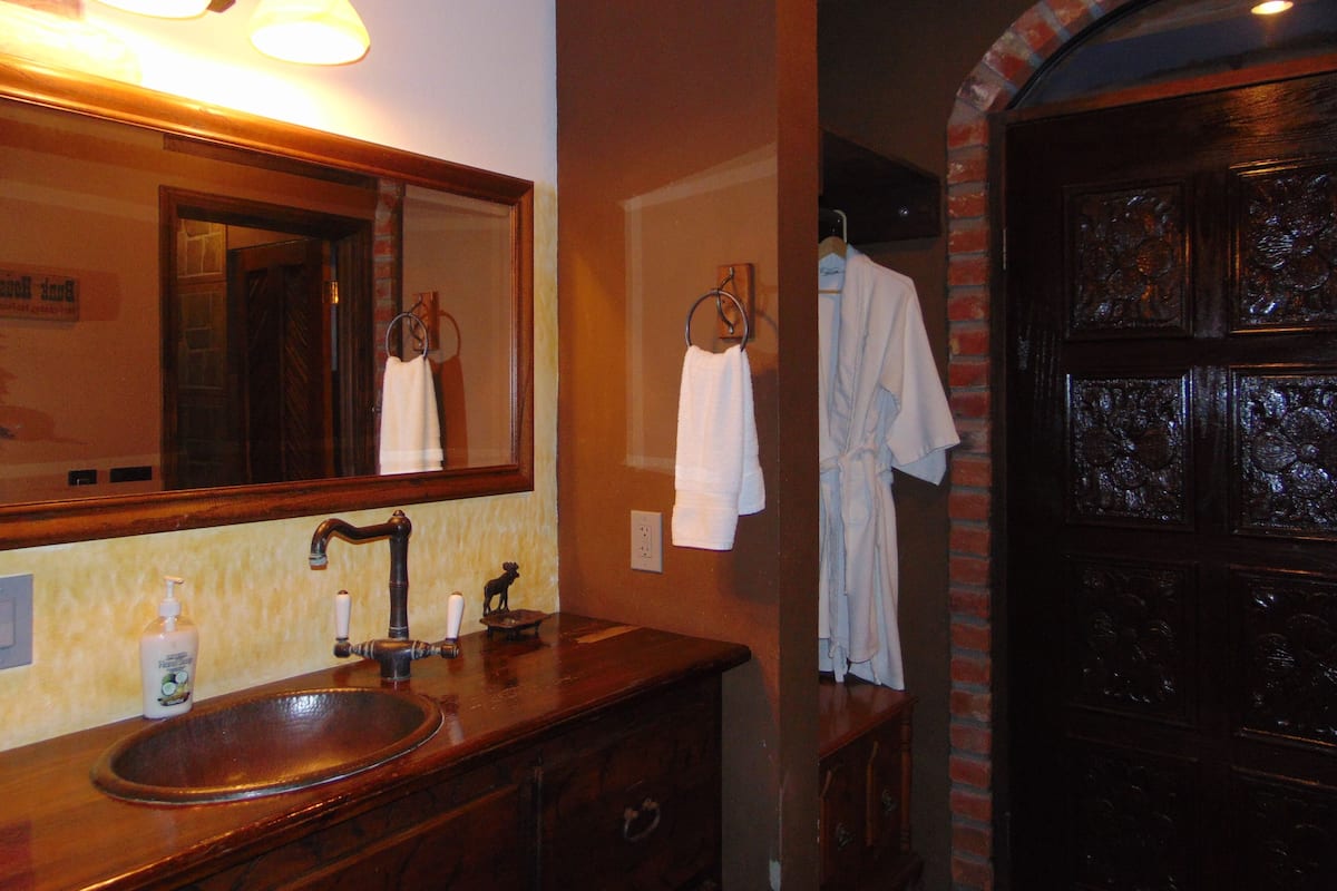 A bathroom with a wooden vanity, a large mirror, a sink, and a towel rack.