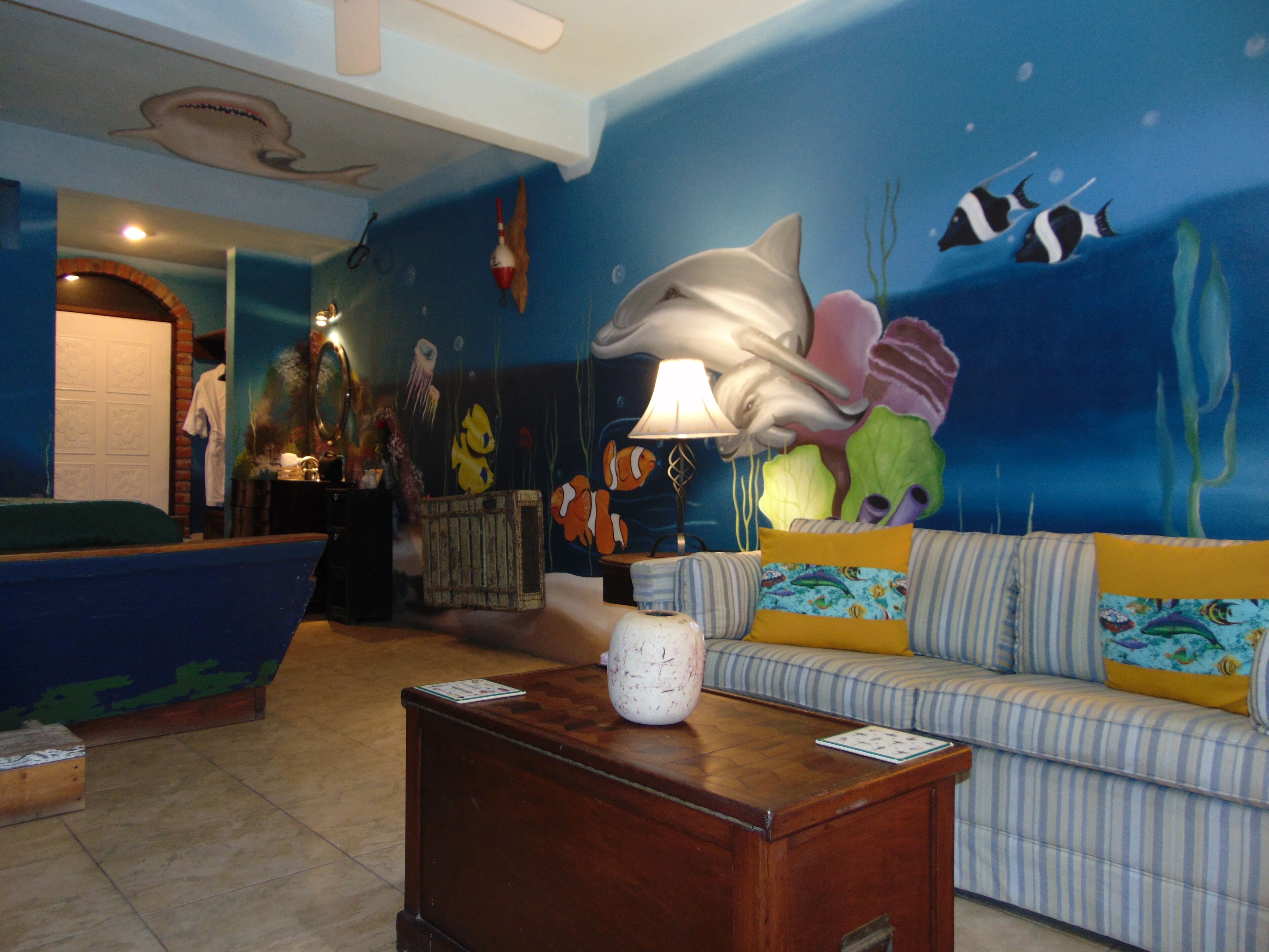 A lobby with a blue mural of marine life, a striped sofa, and a wooden coffee table.