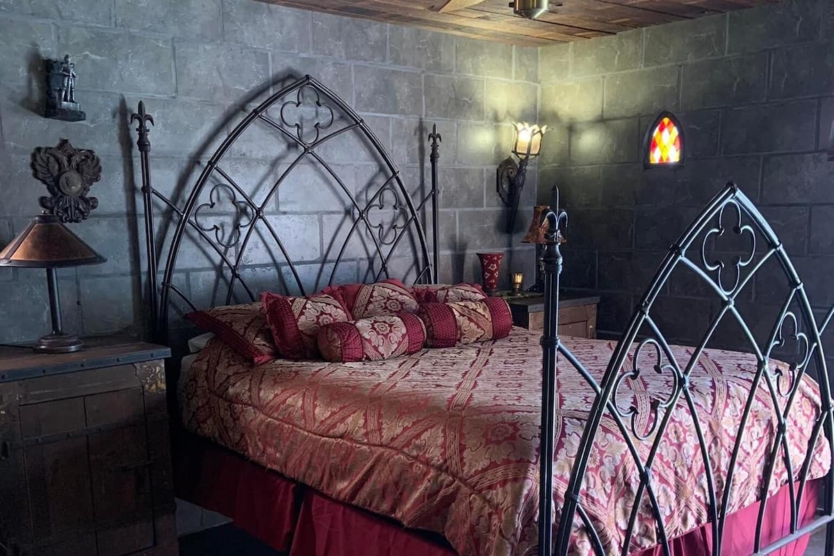 A bedroom with a metal bed frame, a wooden headboard, a ceiling fan, and two rugs.