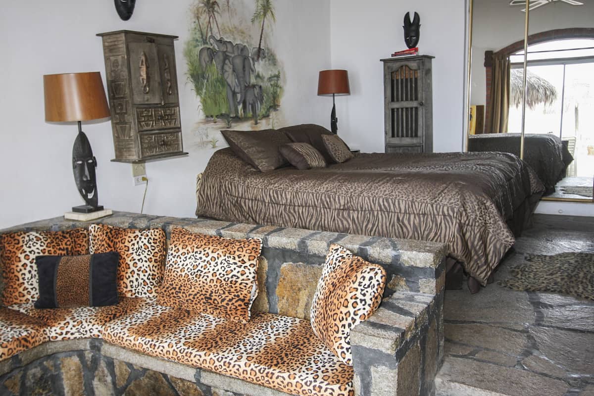 A room with a bed, a stone bench, and a wall with a mural.