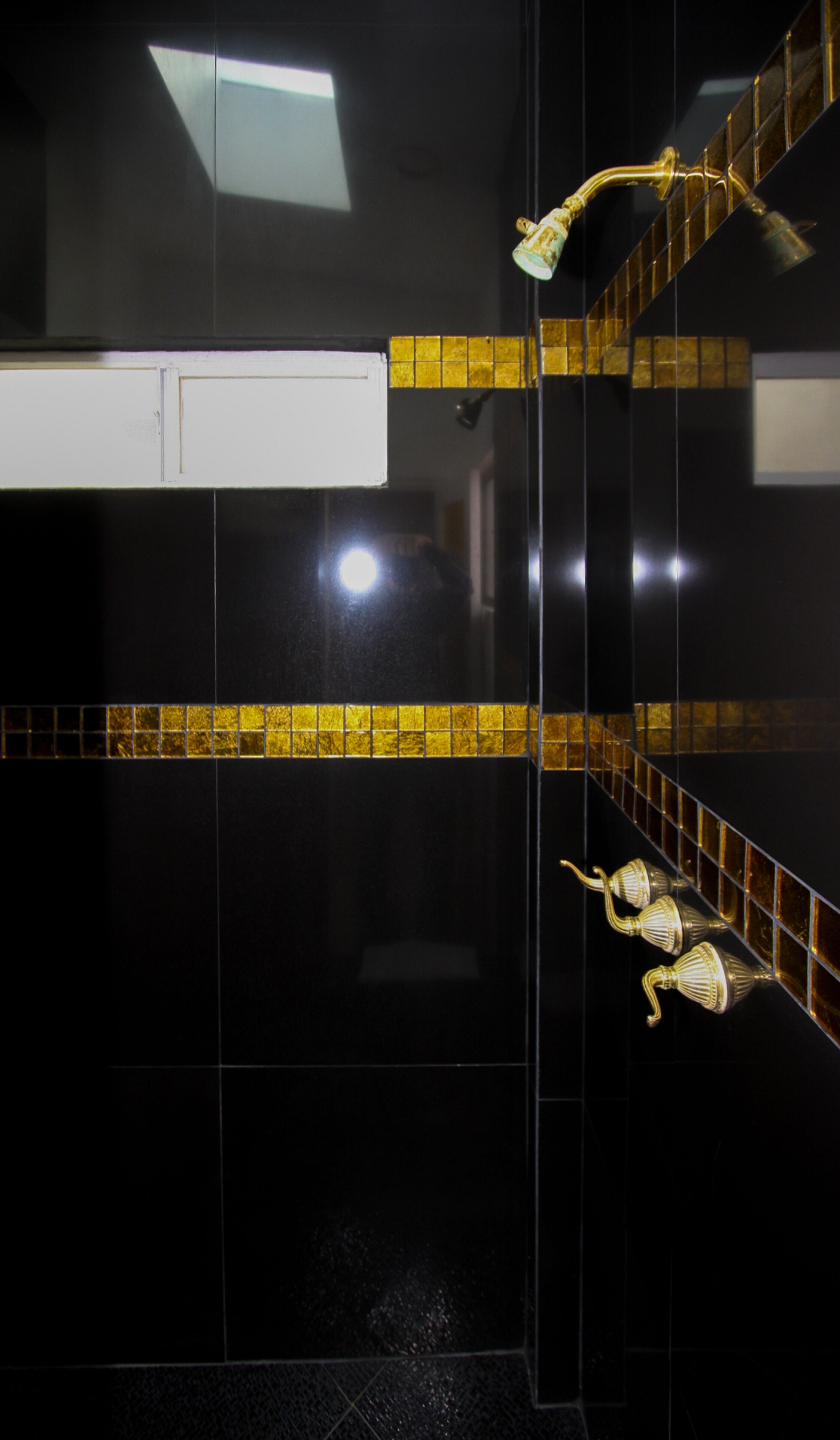 Un bany modern amb rajoles negres, una paret d'accent amb rajoles grogues i un armari blanc.