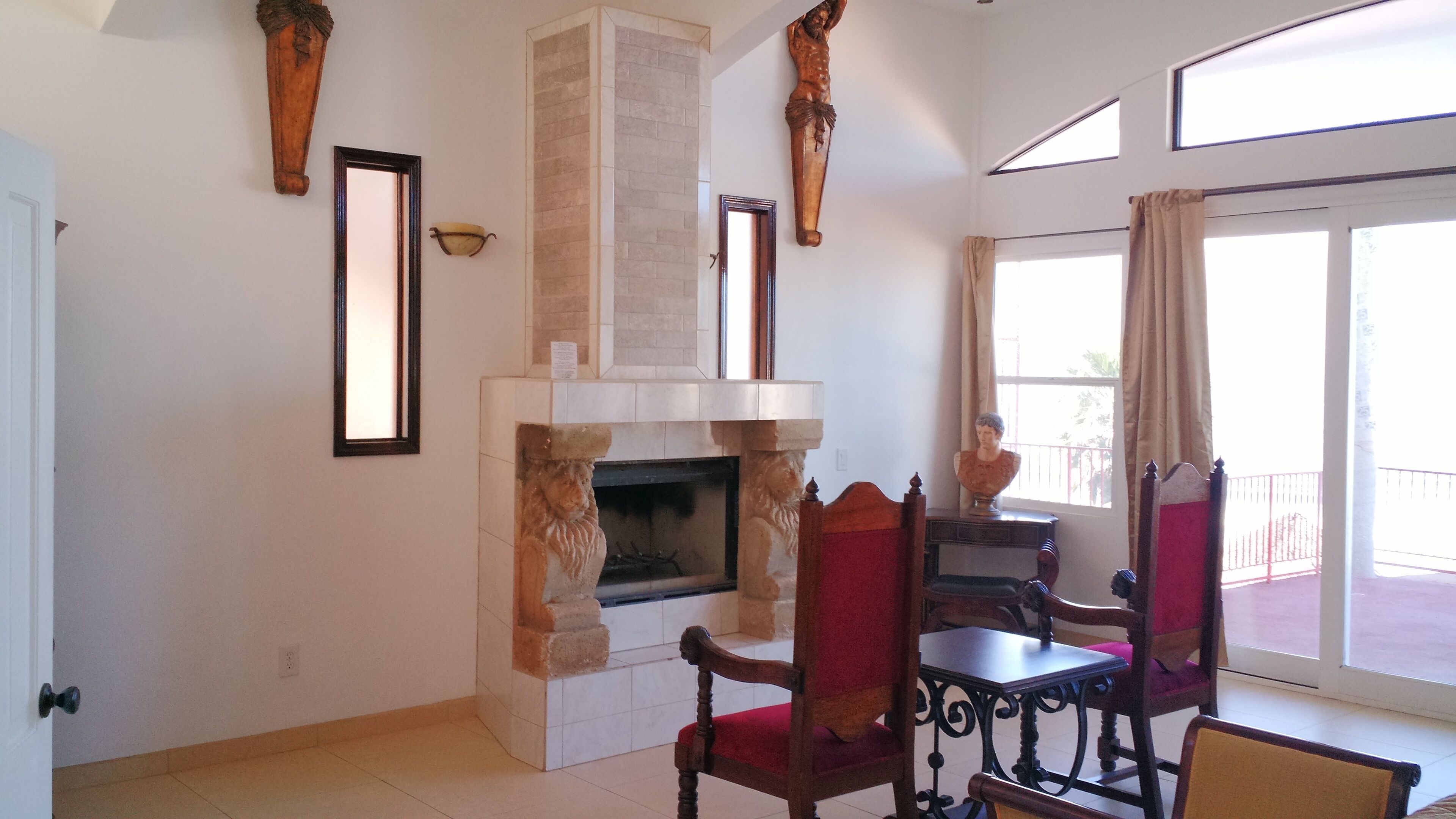Una habitación con chimenea, sillas de madera, una mesa y un ventanal grande.