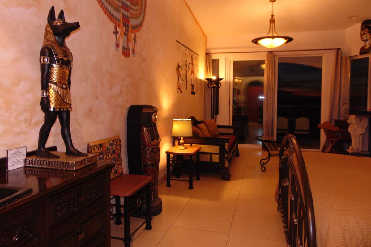 A living room with a statue, a lamp, a sofa, and a dining table.
