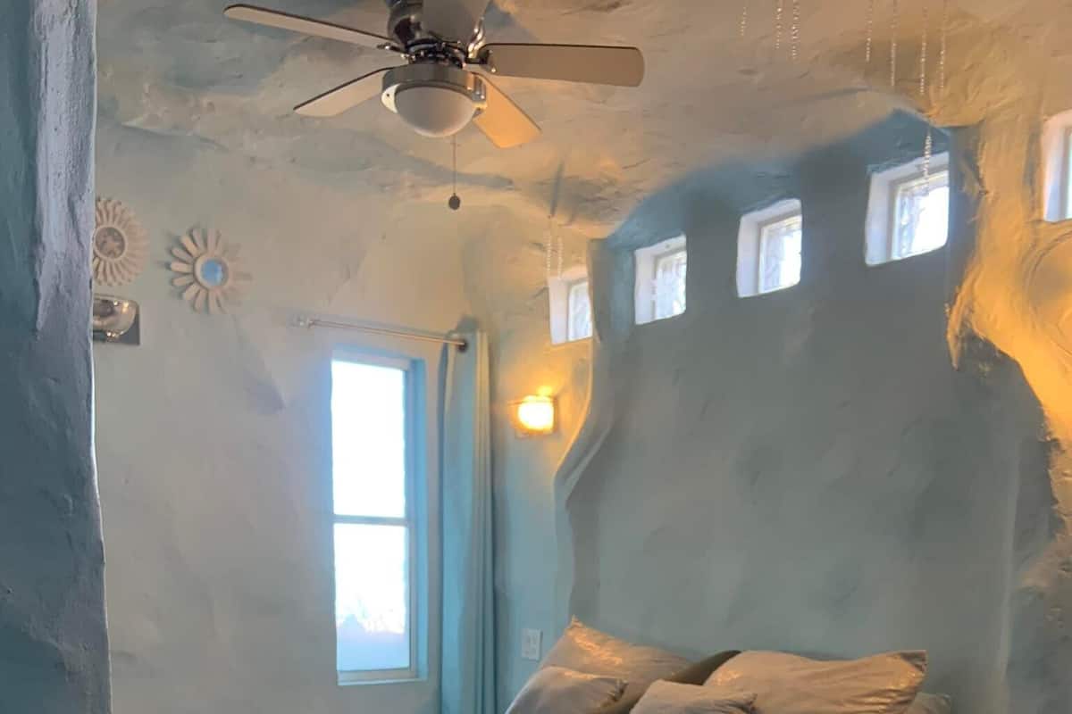 A bedroom with a bed, a ceiling fan, and a window.