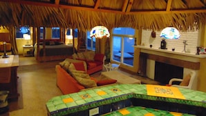 Una habitación acogedora con techo de paja, chimenea y vistas al exterior.