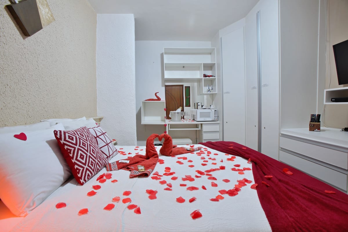 Habitación de hotel con una cama bien hecha, un televisor, un armario y un escritorio con una silla.
