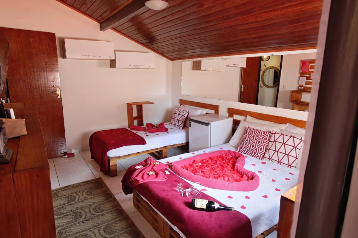 Una habitación con dos camas, techo de madera y un refrigerador pequeño.