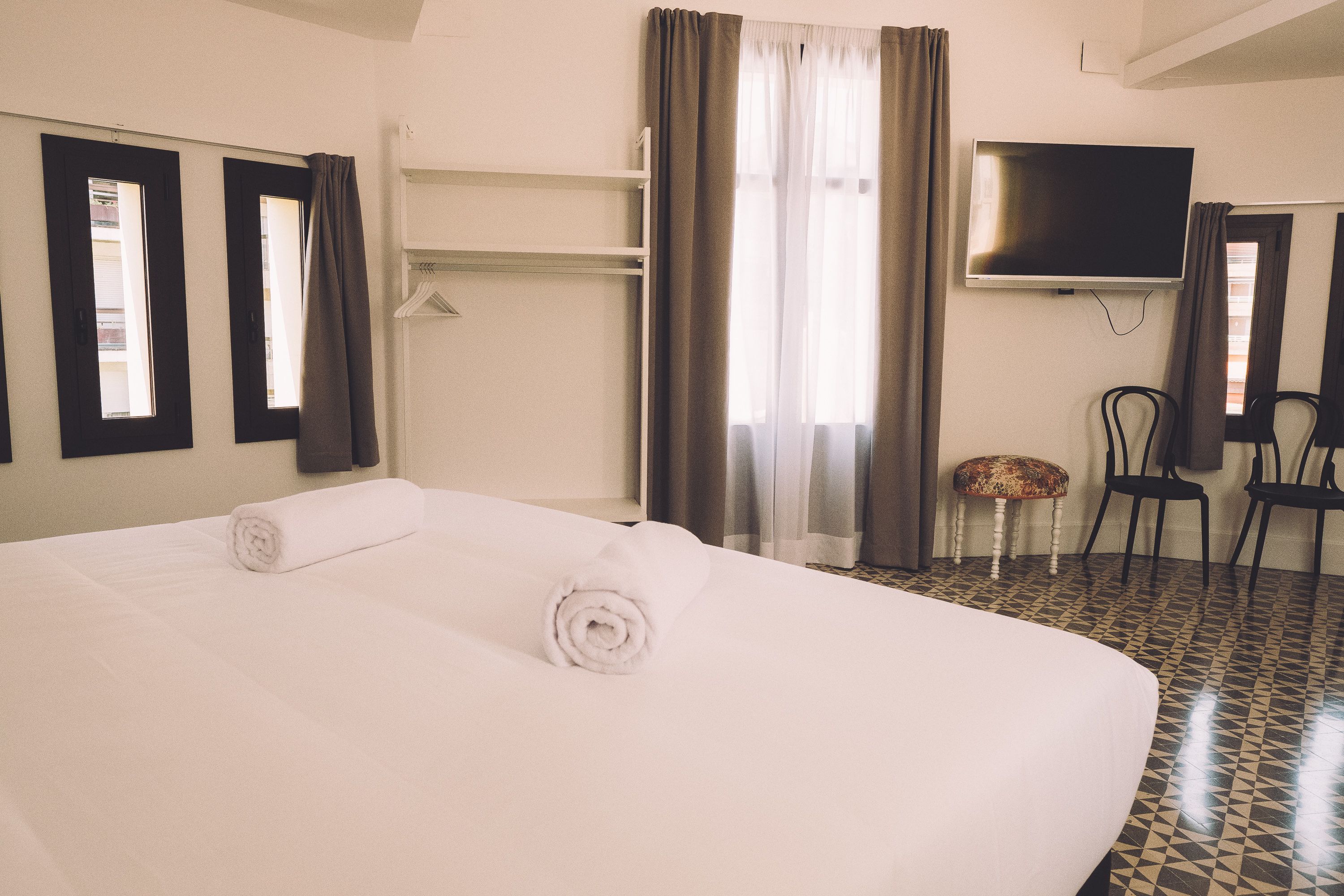 A hotel room with a large bed, a television, a chair, and a small table.