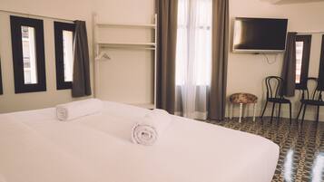 A hotel room with a large bed, a television, a chair, and a small table.