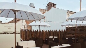 Un espace extérieur aménagé avec des parasols blancs, des canapés confortables et des tables en bois.