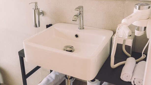 Une salle de bain moderne avec un lavabo blanc, un miroir et un porte-serviettes.