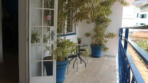 A balcony with potted plants, a table, and a chair. - Pousada Villa Real (Sabara)