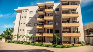 A multi-story residential building with balconies, a flat roof, and a paved driveway. - Marina Flat & Náutica Apartamento - Férias em Caldas Novas (Caldas Novas)