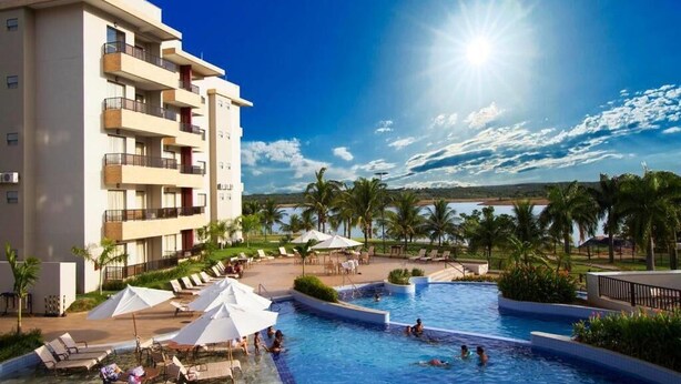 A hotel with a swimming pool, sunbathing areas, and a view of the ocean. - Marina Flat & Náutica Apartamento - Férias em Caldas Novas (Caldas Novas)
