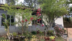 A building with a garden featuring various plants and flowers. - Pousada & Camping Serras Verdes (Valenca)