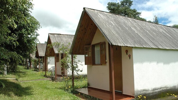A row of small, single-story cabins with sloped roofs, each featuring a porch and a window. - Pousada & Camping Serras Verdes (Valenca)