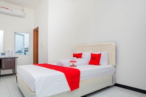 A hotel room with a bed, a bedside table, a mirror, and a window.