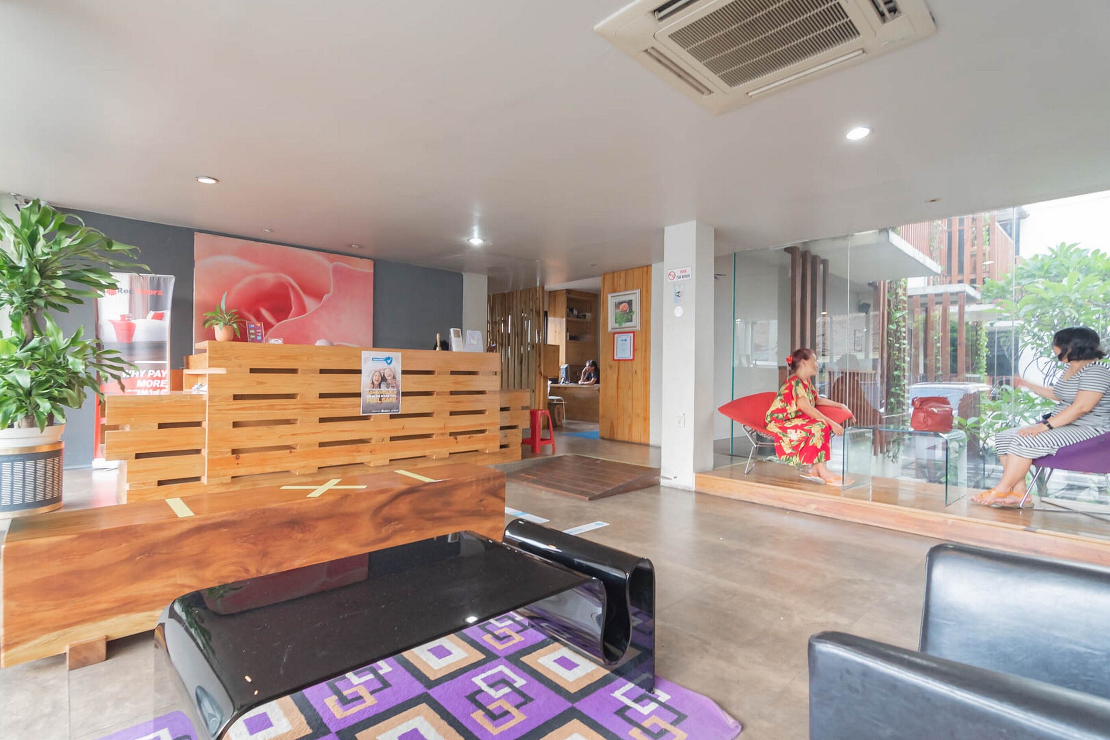 A reception area with a wooden desk, a black bench, and a glass partition.