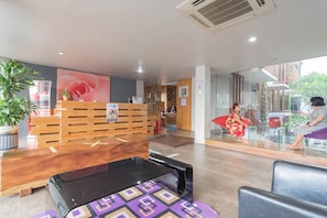 A reception area with a wooden desk, a black bench, and a glass partition. - RedDoorz Plus near Asia Afrika 3 (Bandung)
