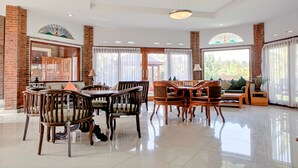 A spacious living area with a high ceiling, large windows, and a mix of wooden furniture. - RedDoorz Plus near Dago Pakar (Bandung)