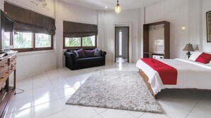 A bedroom with a bed, a dresser, a sofa, and a large window. - RedDoorz Plus near Dago Pakar (Bandung)
