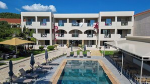 A hotel with a pool, outdoor seating, and a covered patio area. - Remezzo Apartments & Studios (Zakynthos)