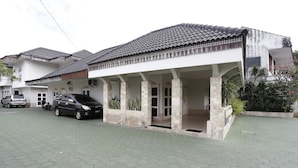 Ein zweistöckiges Haus mit Ziegeldach, einer Veranda und einem gepflasterten Einfahrt.