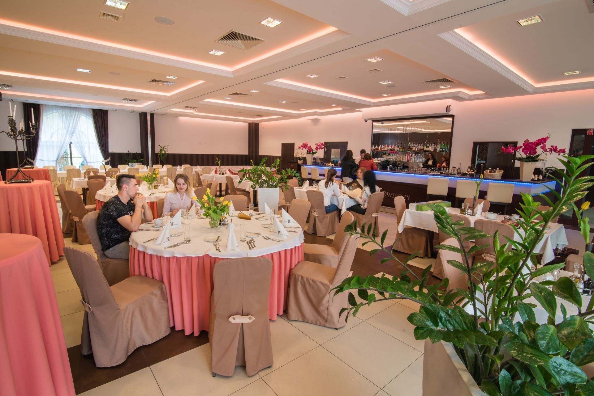 A restaurant with round tables, chairs, and a bar area.
