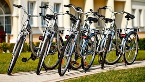 Uma fileira de bicicletas estacionadas em frente a um edifício com colunas e uma placa com a inscrição 'DWOR DWIKOZY'.
