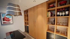 Una cucina moderna con piano cottura integrato, mobili in legno e un espositore per vini con bottiglie e bicchieri.
