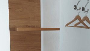 Una scala in legno con pareti bianche e un appendiabiti con grucce.