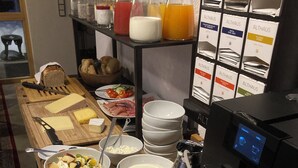 Un'area buffet con diversi cibi, tra cui formaggi, frutta e bevande.