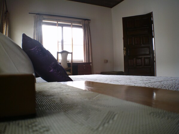 Un dormitorio con cama, una silla, una puerta de madera y una ventana con cortinas.
