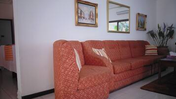 Een woonkamer met een gestreept sofa, een spiegel en twee ingelijste foto's aan de muur.