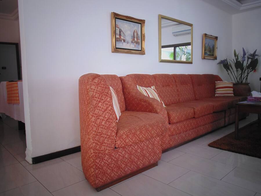 Een woonkamer met een gestreept sofa, een spiegel en twee ingelijste foto's aan de muur.