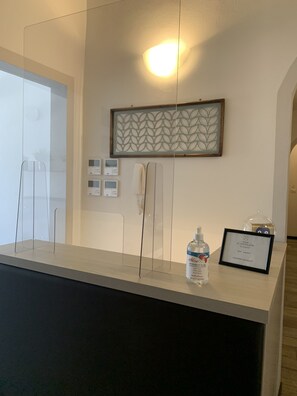 A reception desk with a framed artwork, a bottle of hand sanitizer, and a framed sign with a password. - B&B Dimore le Leopoldine (Florence)