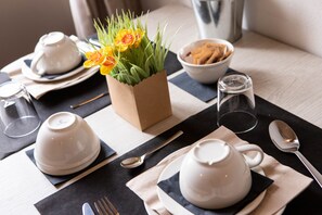 A neatly arranged dining table with white teapots, a bowl of cookies, and a small vase with yellow flowers. - B&B Dimore le Leopoldine (Florence)