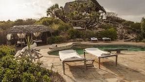 A pool area with lounge chairs, a thatched-roof hut, and a stone pathway. - H12 Delta Dunes Lodge (Kipini)