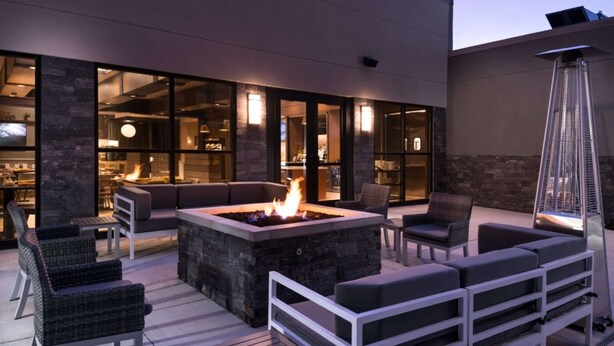 Un patio exterior con un brasero, asientos y vistas al interior.