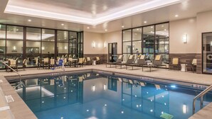 Zona de piscina de hotel con sillas de descanso, un trampolín y agua cristalina.
