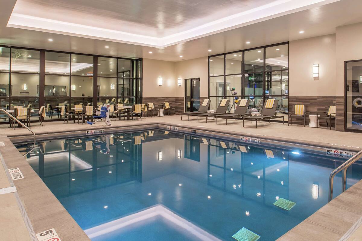 A hotel pool area with lounge chairs, a diving board, and a clear pool.