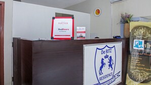 A reception desk with a sign for De Ritz Residence, a RedDoorz sign, and a VIP lounge sign.