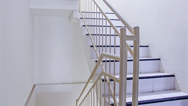 A staircase with white steps and a wooden handrail.