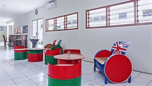A room with a tiled floor, a dining area with chairs and a table, and a window with blinds.