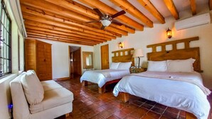 A room with two beds, a sofa, wooden ceiling beams, and a tiled floor. - La Provence Restaurant & Boutique Hotel (Cuernavaca)