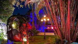 A garden with a decorative spherical structure, a pathway, and palm trees. - La Provence Restaurant & Boutique Hotel (Cuernavaca)