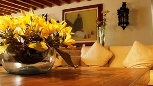 A wooden table with a glass vase of yellow flowers, a framed picture on the wall, and a beige sofa. - La Provence Restaurant & Boutique Hotel (Cuernavaca)